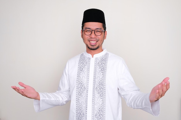 Hombre asiático musulmán sonriendo feliz con ambas manos abiertas haciendo pose de saludo