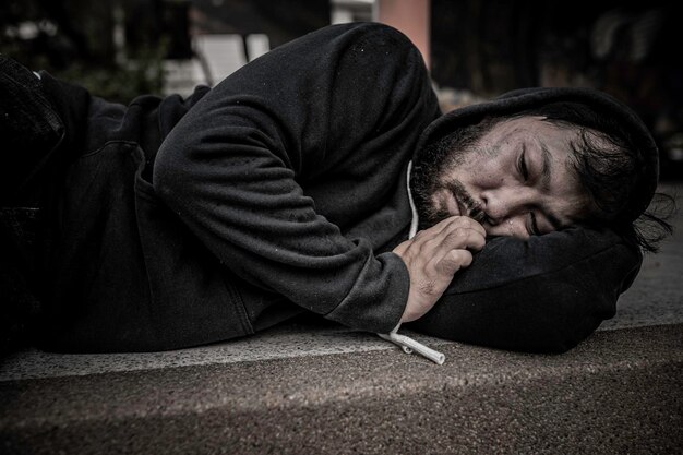 Un hombre asiático no tiene hogar en la calle lateral. Un extraño tiene que vivir solo en la calle porque no tiene familia.