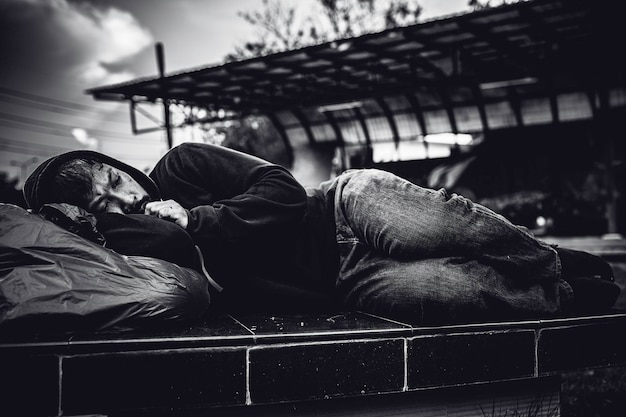 Un hombre asiático no tiene hogar en la calle lateral. Un extraño tiene que vivir solo en la calle porque no tiene familia.