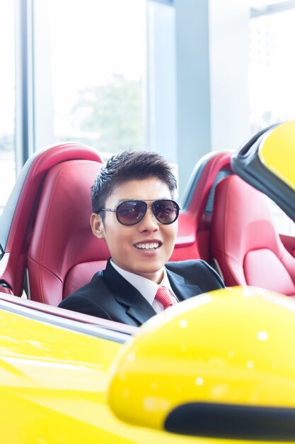 Hombre asiático probando nuevo auto deportivo