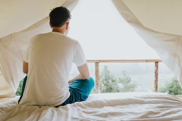 Hombre asiático que mira Mountain View de la tienda en tiempo de la puesta del sol