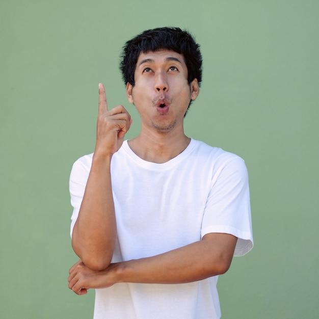 Hombre asiático que mira la vista superior y el dedo apunta a la vista superior para la promoción de venta. Imagen de trazado de recorte aislado.
