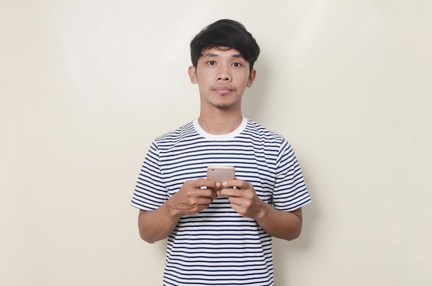 Hombre asiático que muestra una expresión triste con el móvil en la mano
