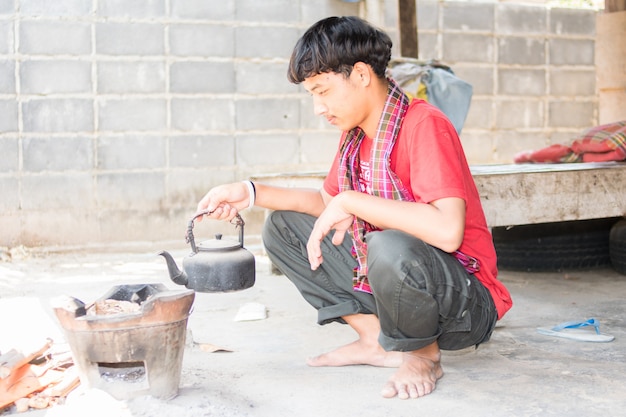 Hombre asiático que se sienta y que cocina en cocina vieja