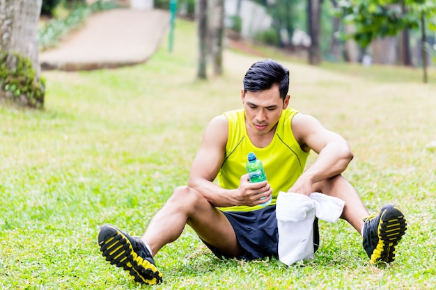 Hombre asiático que tiene descanso de entrenamiento deportivo