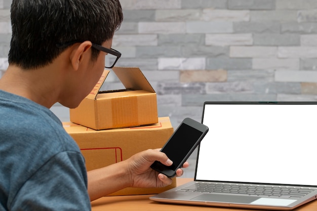 Foto hombre asiático que usa un teléfono inteligente que toma la comprobación de la orden de compra en línea de los clientes