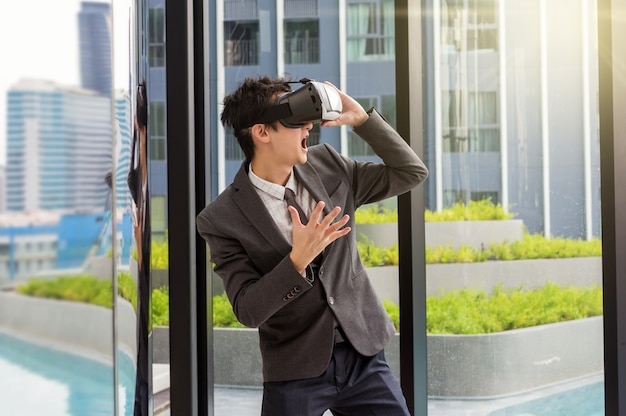 Hombre asiático con realidad virtual con traje de negocios en el edificio moderno