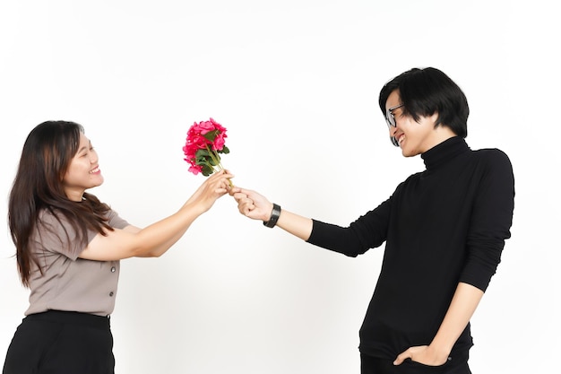 Hombre asiático regalo una flor para mujer aislado sobre fondo blanco.