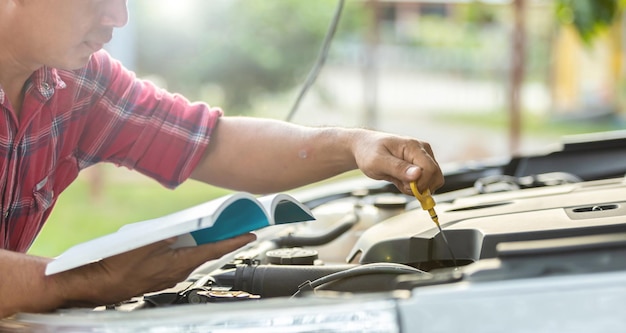 Hombre asiático revisando su automóvil o arreglando el motor de un automóvil moderno antes de comenzar el viaje