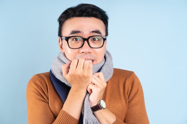 Hombre asiático con ropa de invierno sobre fondo azul.