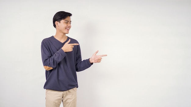 Hombre asiático señalando el espacio en blanco al lado aislado sobre fondo blanco.