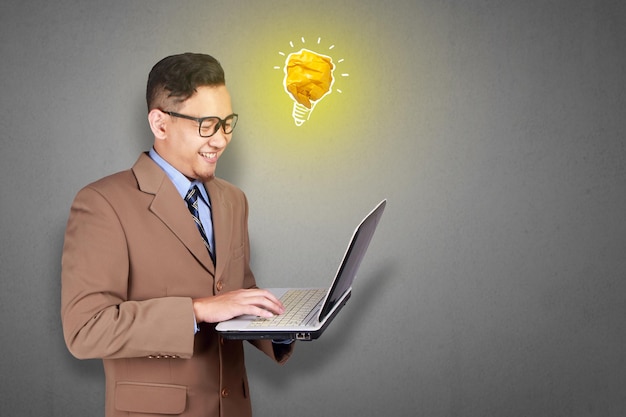 Hombre asiático sonriendo feliz con una lámpara de bombilla brillante hecha de papel símbolo de idea e innovación