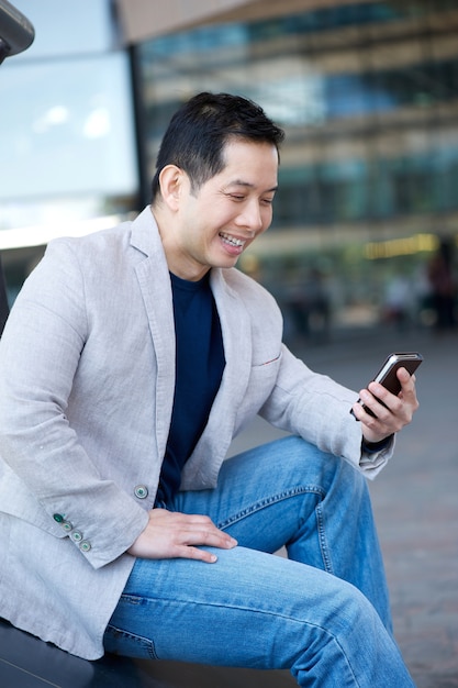 Hombre asiático sonriendo con teléfono móvil