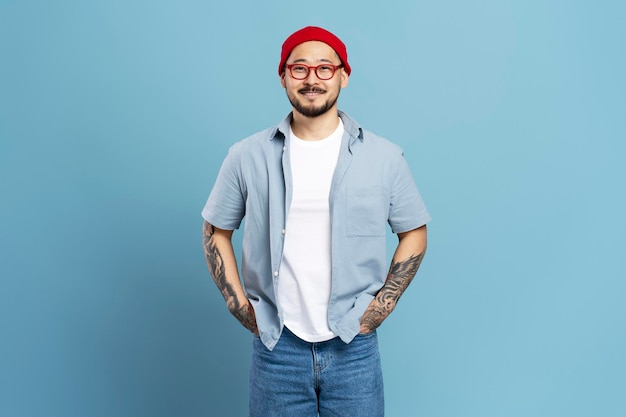 Hombre asiático sonriente con tatuaje elegante aislado en el espacio de copia de fondo azul