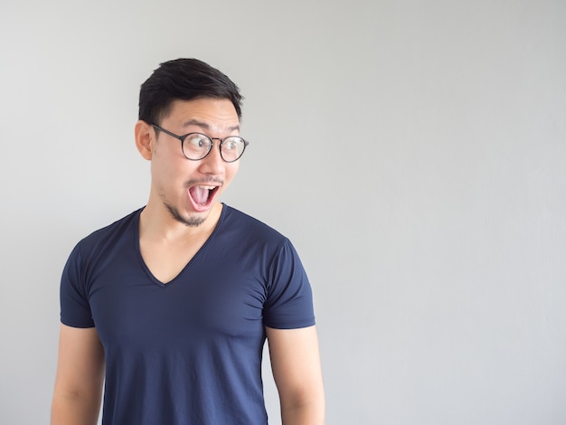 Hombre asiático sorprendido y sorprendido con las lentes y la barba que miran en copyspace.