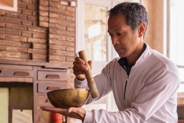 Foto hombre asiático tocando un cuenco tibetano que canta