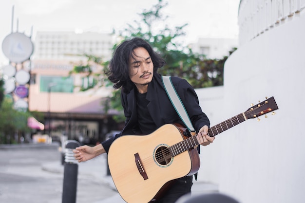 Hombre asiático tocando la guitarra festival de música en la calle
