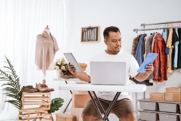 Hombre asiático trabajando en una computadora portátil en una tienda de ropa