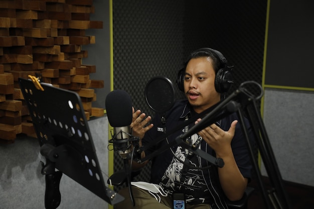 Foto hombre asiático trabajando en una estación de radio y hablando con sus fans