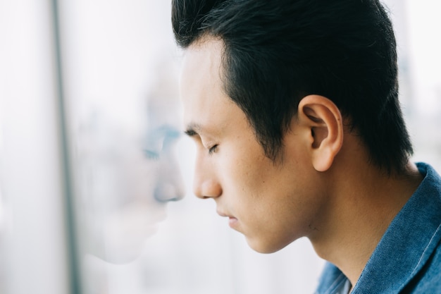 Hombre asiático triste por la ventana