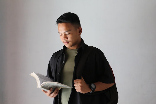 Foto hombre asiático universitario leyendo un libro