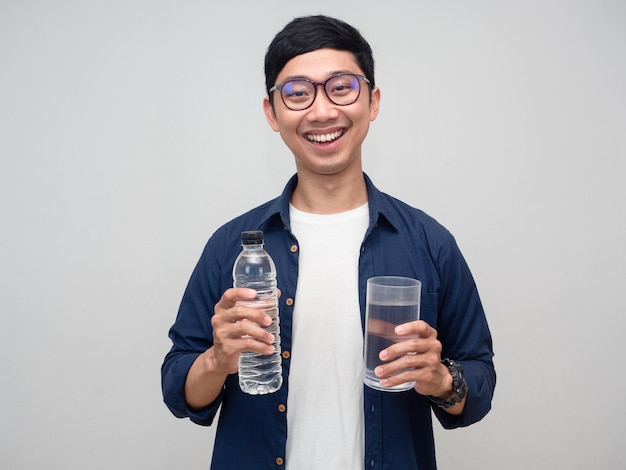 El hombre asiático usa anteojos sonrisa feliz sostiene la botella de agua con un vaso de agua aislado