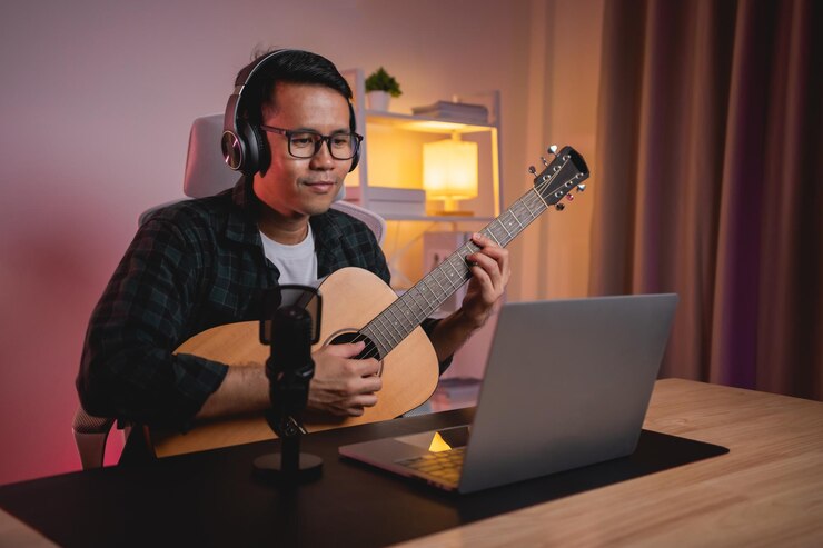 Foto hombre asiático youtuber transmisión en vivo actuación tocando la guitarra y cantando una canción hombre asiático enseñando guitarra y cantando en línea músico grabando música con computadora portátil y tocando guitarra acústica