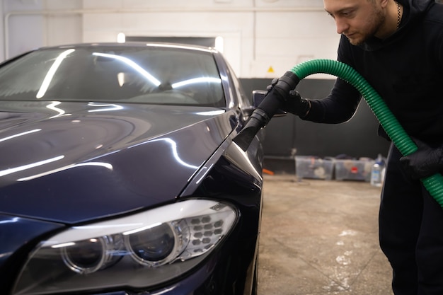 Hombre con aspiradora elimina las gotas de agua del coche.