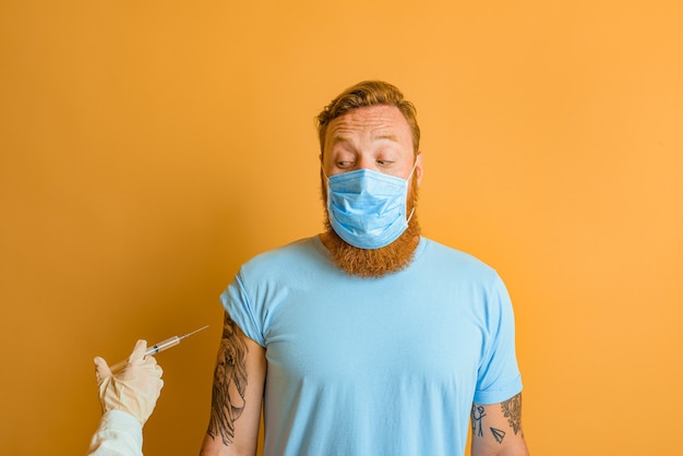 Hombre asustado con tatuaje de barba y máscara para covid está listo para la vacuna contra el virus