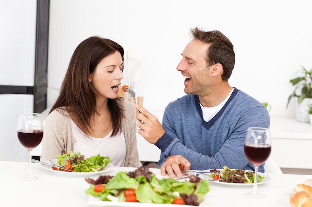 Hombre atento dando un tomate a su novia mientras almorzaba