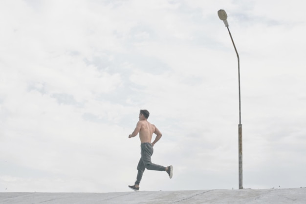 Hombre atleta asiático trotando por la mañana al aire libre, estilo de fotografía minimalista de corredor kazajo