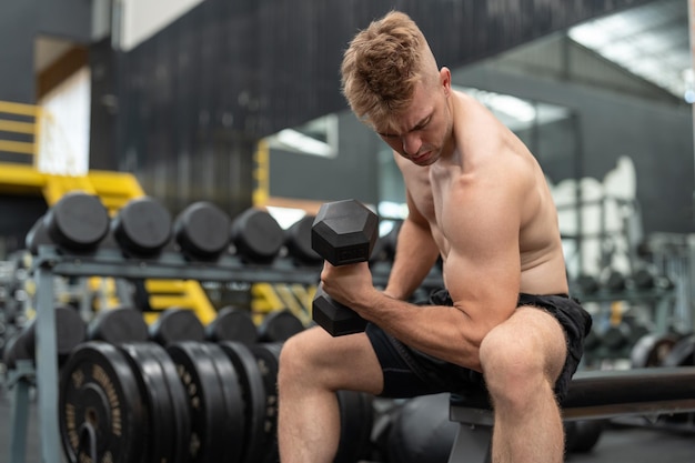 Foto hombre atleta boxeador sin camisa haciendo ejercicio con pesas en el gimnasio