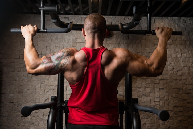 Hombre atleta haciendo pull ups ChinUps en el gimnasio