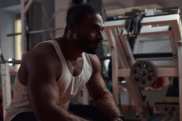 Foto un hombre atleta con piel oscura se sienta en el gimnasio y espera el concepto de deporte y estilo de vida saludable h ...