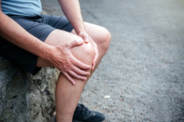 Un hombre atleta que sufre de desgarro del ligamento de la rodilla.