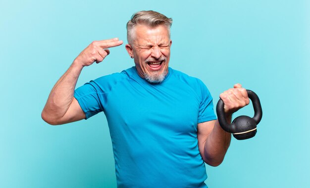 Hombre atleta senior mirando infeliz y estresado, gesto de suicidio haciendo signo de pistola con la mano, apuntando a la cabeza