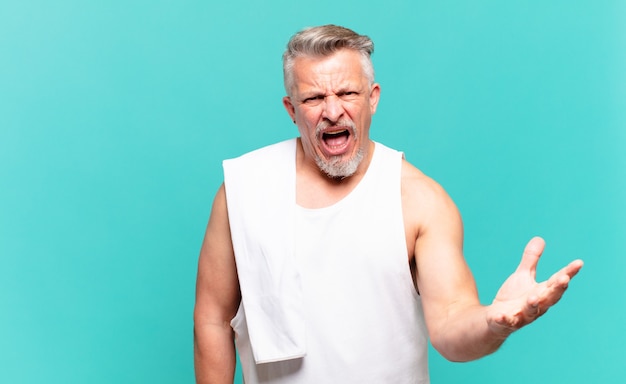 Hombre atleta senior que parece enojado, molesto y frustrado gritando wtf o qué te pasa