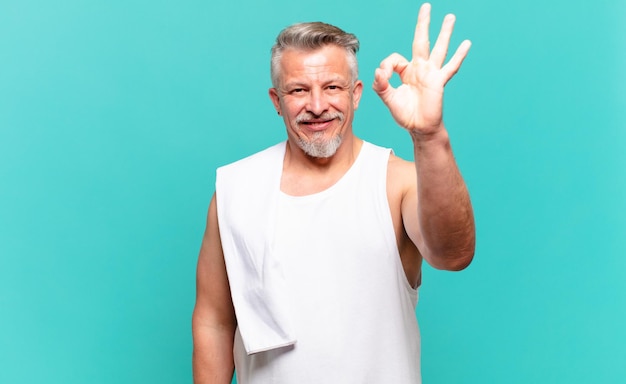 Hombre atleta senior que se siente feliz, relajado y satisfecho, mostrando aprobación con gesto bien, sonriendo