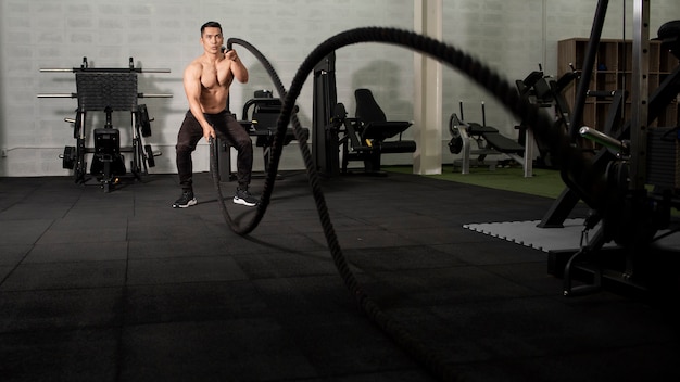 Hombre atlético asiático con cuerda haciendo ejercicio en el gimnasio