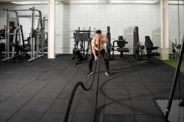 Hombre atlético asiático con cuerda haciendo ejercicio en el gimnasio