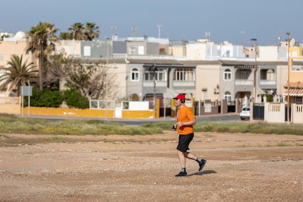 Hombre atlético corriendo en el parque con auriculares en un día soleado de verano Estilo de vida saludable Los hombres adultos activos están trotando
