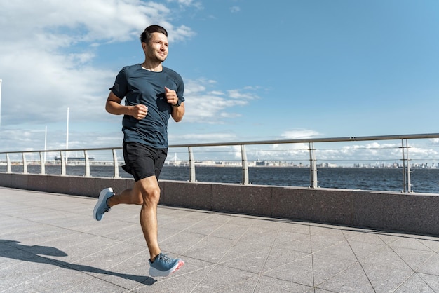 Hombre atlético corriendo en un paseo marítimo con un cielo despejado personificando la dedicación y un