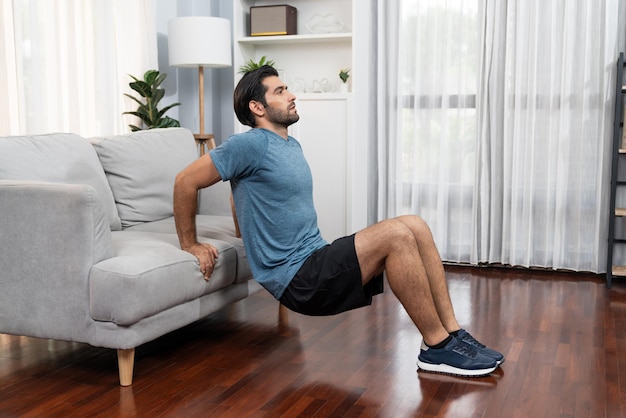 Hombre atlético y deportivo activo que utiliza muebles para el ejercicio doméstico alegre