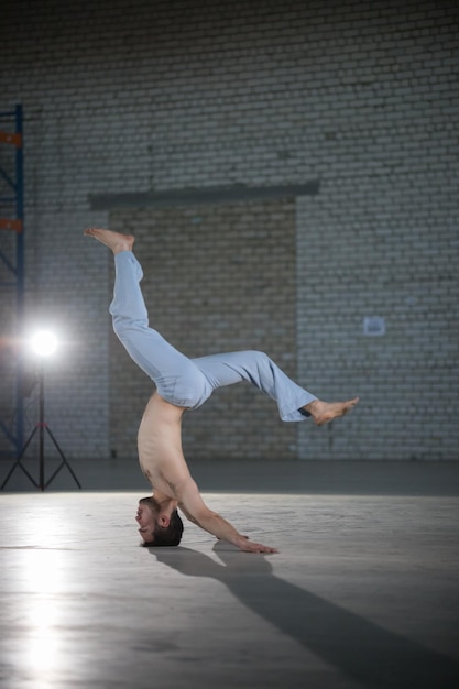 Un hombre atlético en el entrenamiento de capoeira realizando un stand en la cabeza con la columna doblada