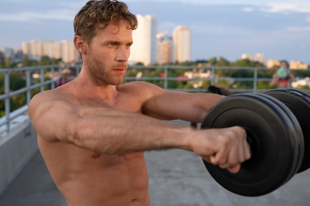 Foto hombre atlético entrenando al aire libre con pesas