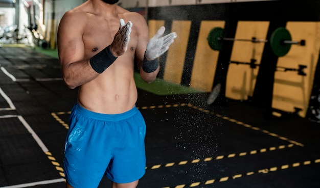 Hombre atlético en gimnasio con manos de magnesio