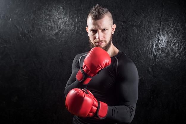 Un hombre atlético con guantes rojos de kickboxing posando y listo para pelear en el gimnasio