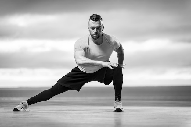 Foto hombre atlético haciendo ejercicios de fitness en la playa del océano