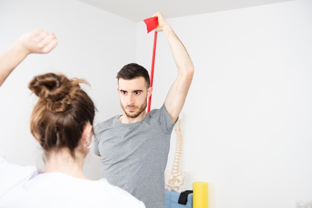 Hombre atlético haciendo ejercicios de rehabilitación con una banda elástica. Tratamiento de estiramiento de pilates.