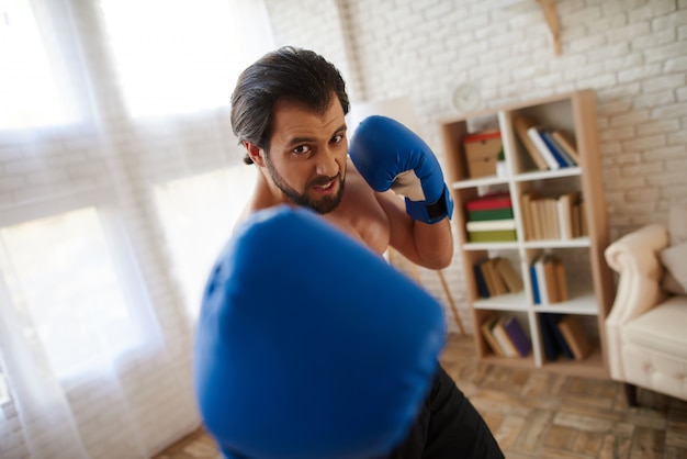 El hombre atlético hermoso en guantes de boxeo hace el sacador.